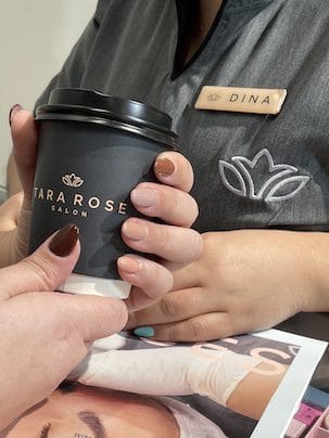 A Tara Rose coffee cup held by a client with a fresh manicure